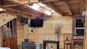 A cozy log cabin interior with a sofa, a small table, a fireplace, and a television mounted on the wall. - Beautiful Montana Cabin, at the base of the Pintler Mountains (Anaconda)