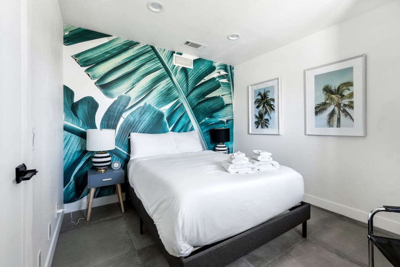A modern bedroom with a large bed, a nightstand with a lamp, and two framed pictures on the wall.