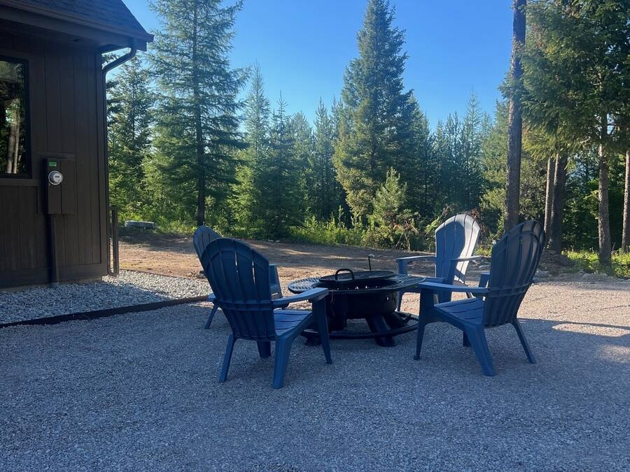 Un patio de grava con sillas Adirondack y un pozo de fuego.