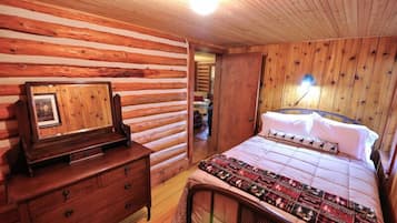 Een slaapkamer in chaletstijl met een bed, een dressoir en een ingelijste foto aan de muur.