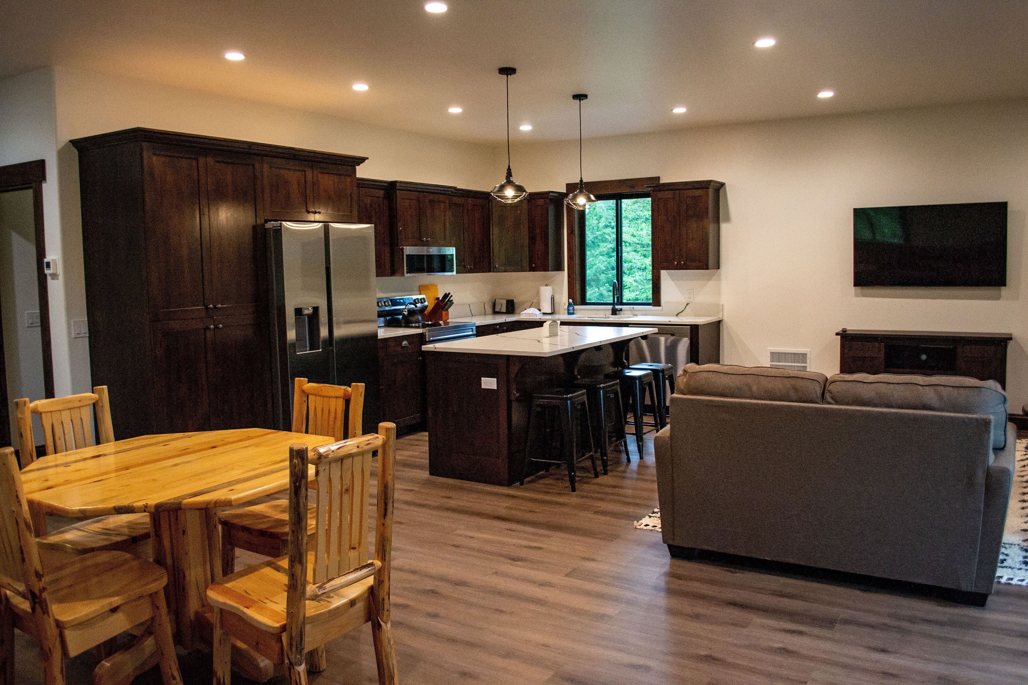 A modern kitchen with dark wood cabinets, a central island, and pendant lighting.