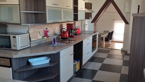 Una cocina moderna con piso de cuadros, microondas, hervidor y cafetera.