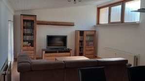 Una sala de estar con un sofá modular, un televisor y estanterías de madera.