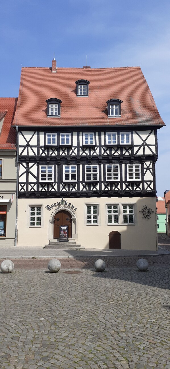 A traditional half-timbered building with a tiled roof, a central entrance with a door, and multiple windows. - Family friendly apartment in Köthen (Köthen)