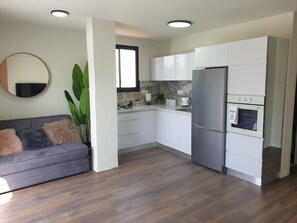 A modern kitchen with white cabinets, a stainless steel refrigerator, and a built-in oven.