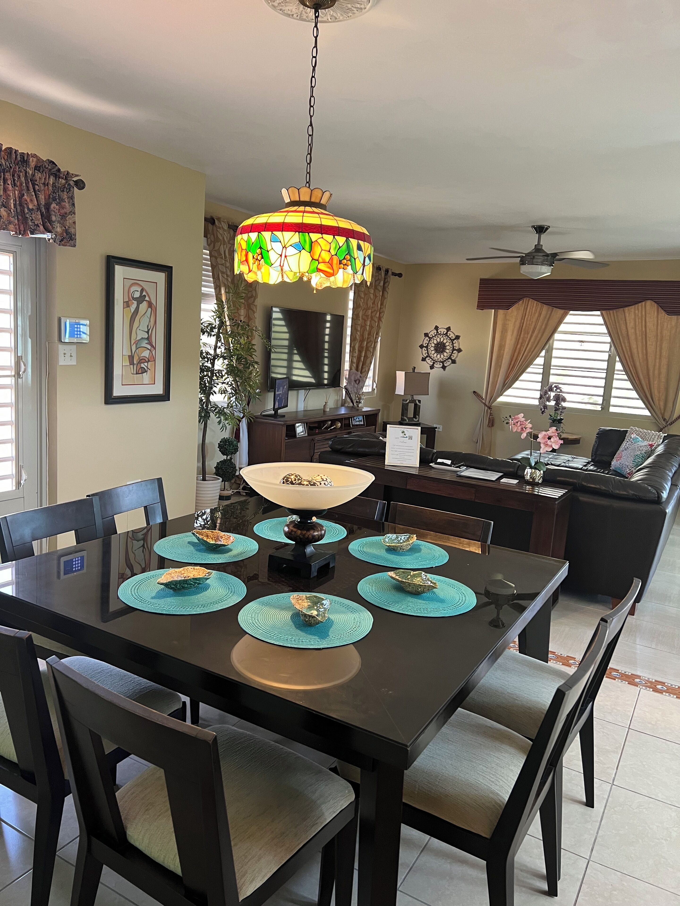 A dining area with a table set for four, a chandelier, and a television in the background.