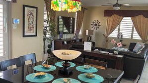 A dining area with a table set for four, a chandelier, and a television in the background.