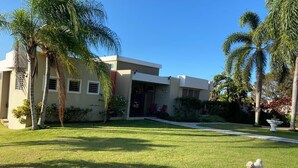 A modern house with a well-maintained lawn and palm trees.