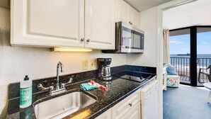 Une cuisine équipée d’un évier, d’une cuisinière, d’un four à micro-ondes et offrant une vue sur l’océan.