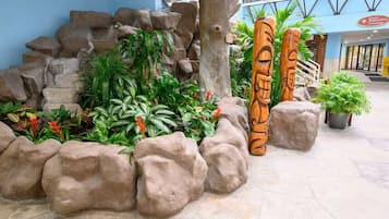 A tropical-themed indoor garden with rock formations and wooden totems.