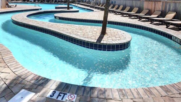 A swimming pool with a tiled edge, palm trees, lounge chairs, and a '3 FT NO DIVING' sign.