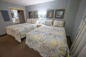A hotel room with two beds, a mirror, and artwork on the wall.