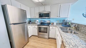 A kitchen with white cabinets, stainless steel appliances, granite countertops, and a double sink.