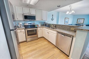 A modern kitchen with white cabinets, stainless steel appliances, and a granite countertop.
