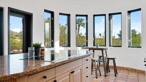 Una cocina moderna con una isla grande, varios ventanales y vistas al exterior.