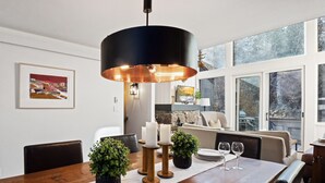 Ein Essbereich mit Holztisch, Kerzen, Topfpflanzen und einer modernen Pendelleuchte.