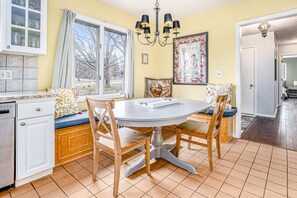 Enjoy meals together at the dining table for four, surrounded by a stylish kitchen with appliances and a beautiful chandelier.