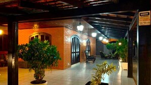 An indoor corridor with tiled flooring, potted plants, and a brick wall. - Casa com Piscina em Penha - Beto Carrero (Penha)