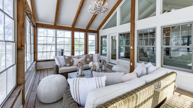 Una habitación amplia con ventanas grandes, techo de madera y un candelabro.