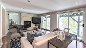 Una sala de estar moderna con chimenea, ventanas amplias y un televisor de pantalla plana.