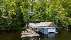 Una casa flotante con terraza y escaleras, rodeada de un bosque frondoso.
