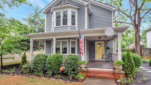 A two-story house with a front porch, a small front yard with potted plants, and an American flag. - Adorable Atlanta gem near downtown with WiFi, backyard, & excellent location (Atlanta)