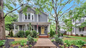A two-story house with a front porch, a front yard with a pathway leading to the door, and a small garden area with stepping stones. - Adorable Atlanta gem near downtown with WiFi, backyard, & excellent location (Atlanta)