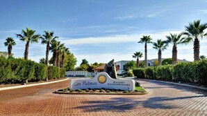 Las Palmas Resort -lomahuoneistojen opaste, jossa on asfaltoitu sisäänkäynti ja palmuja.