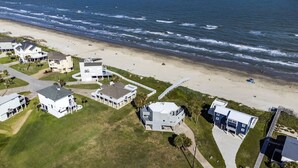 Oversigtsbillede af et kystnære boligområde med ejendomme direkte ud til stranden, herunder huse med altaner og en promenade, der fører til stranden.