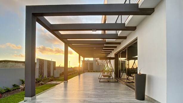A covered outdoor area with a patio, a swing set, and a view of the sunset. - Villa de la Ponte by Atlantic Holiday (Estreito Calheta)