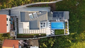 An aerial view of a modern house with a rooftop pool, outdoor seating area, and a small garden. - Villa de la Ponte by Atlantic Holiday (Estreito Calheta)