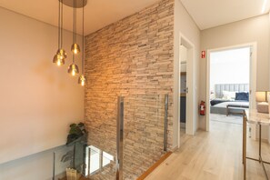 Un intérieur moderne avec un mur en pierre, une rambarde en verre et un plancher en bois.
