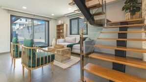 A modern living room with a staircase, a sofa, a coffee table, and a bookshelf. - Villa de la Ponte by Atlantic Holiday (Estreito Calheta)