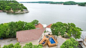 Une maison avec une terrasse autour de la piscine, un quai pour bateaux et une vue sur un lac.