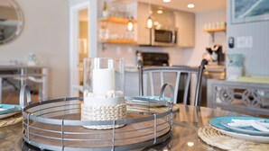 A dining area with a glass table, metal chairs, and a candle centerpiece. - Lands' End @ Sunbird :5th floor Sleeps 4 Gulf Front (Panama City)