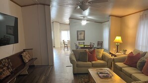 A living room with a sofa, a coffee table, a TV, and a ceiling fan. - Biloxi Shuckers walk to the Blue Wahoos stadium!Close to Navy Base & Beaches. (Pensacola)