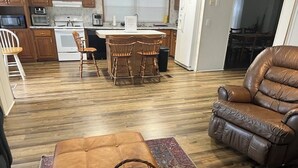 A living room with a brown leather sofa, a wooden dining table with four chairs, and a kitchen in the background. - Biloxi Shuckers walk to the Blue Wahoos stadium!Close to Navy Base & Beaches. (Pensacola)