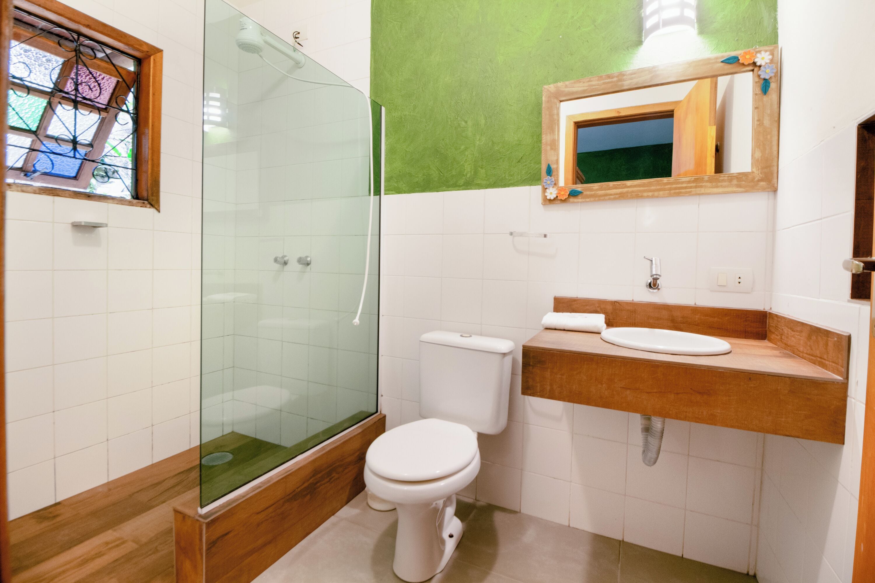 Een badkamer met een douchecabine van glas, een wit toilet en een houten wastafelmeubel met een wastafel.