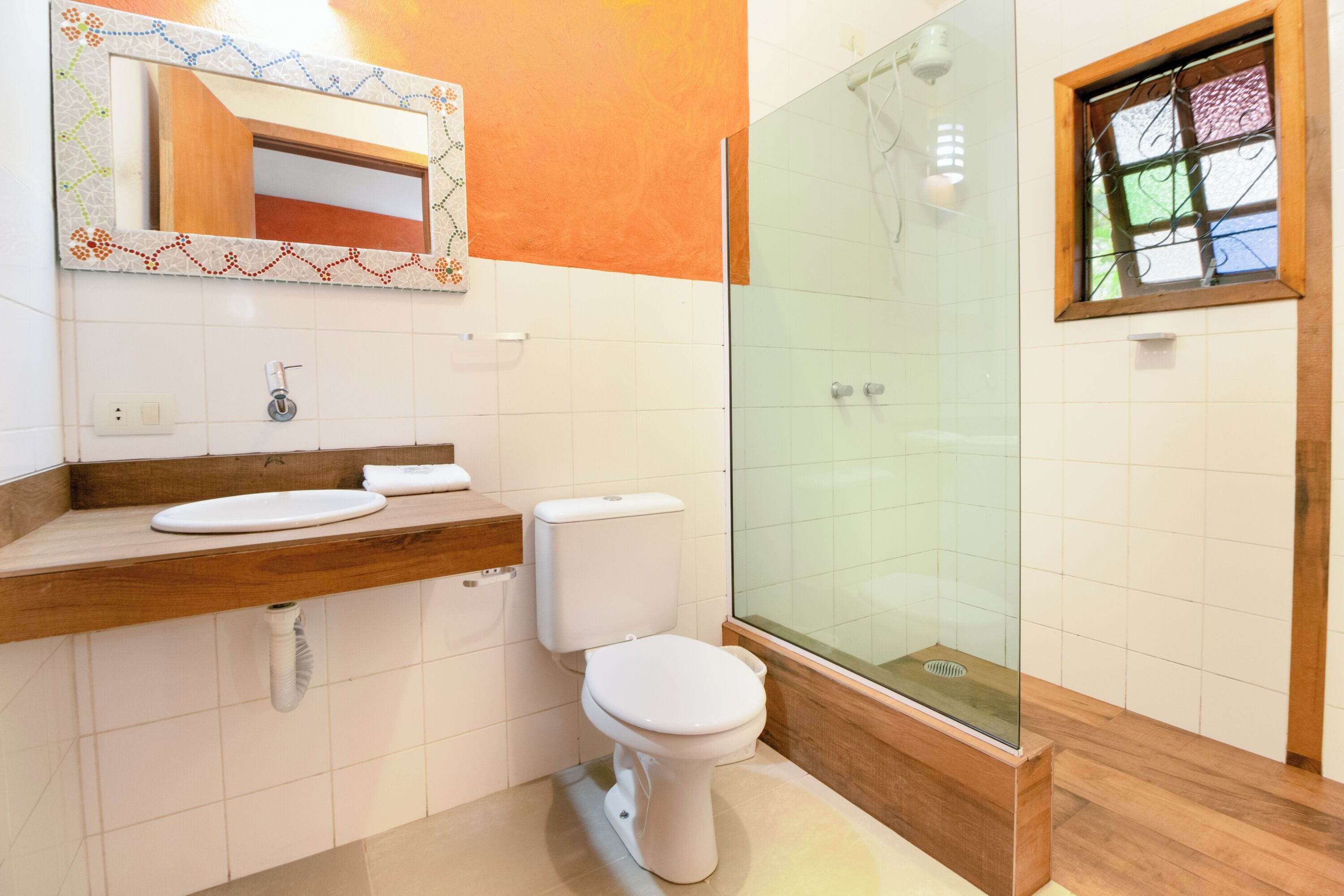 A bathroom with a wooden vanity, white toilet, and a glass-enclosed shower.