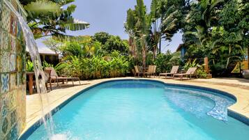 Een buitenzwembad, parasols bij het zwembad en ligstoelen