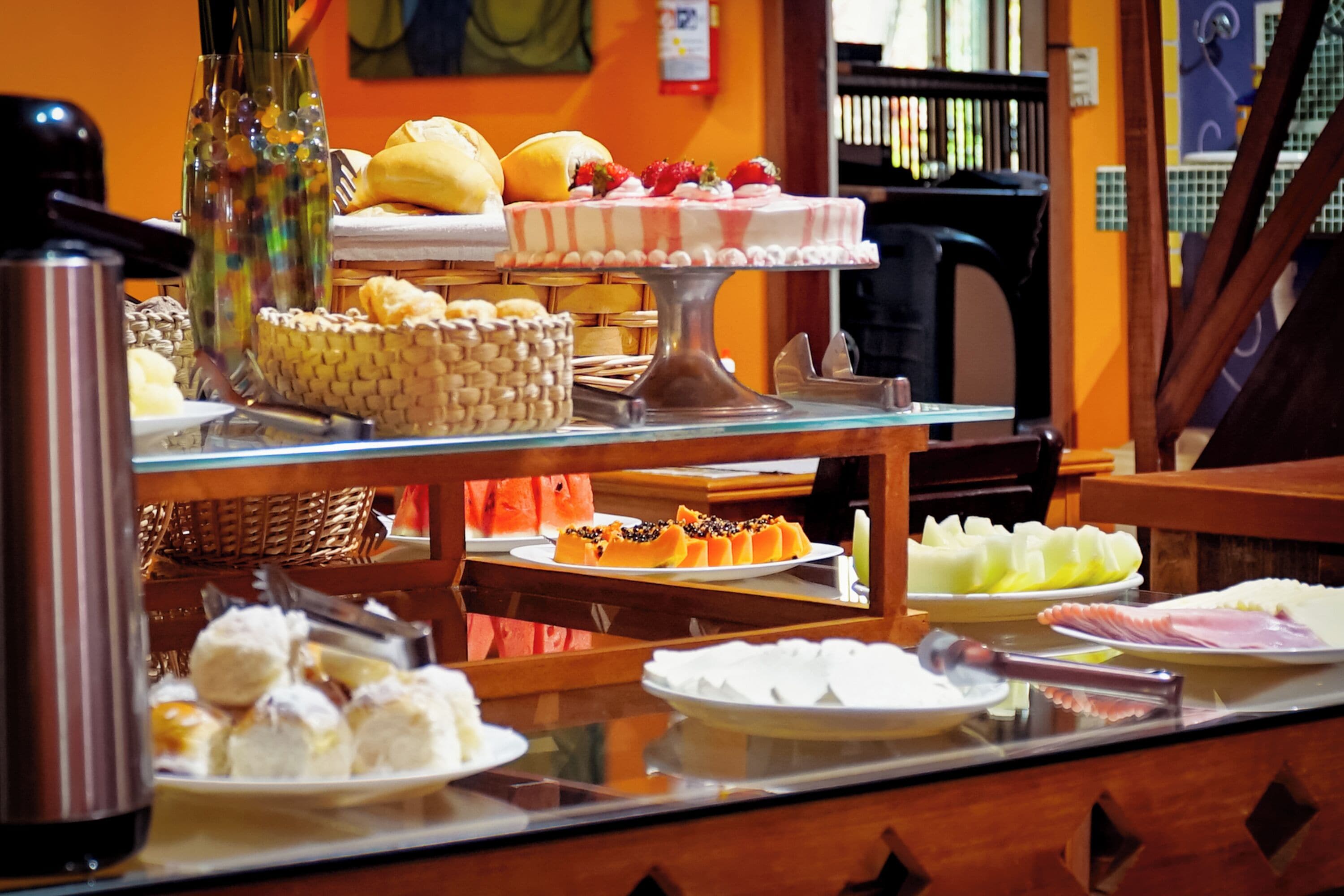 A buffet with various food items including pastries, fruits, and a cake.