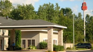 Un hôtel doté d’une entrée couverte, d’une enseigne indiquant « American Heritage Inn », et d’un parking où se trouve un véhicule.