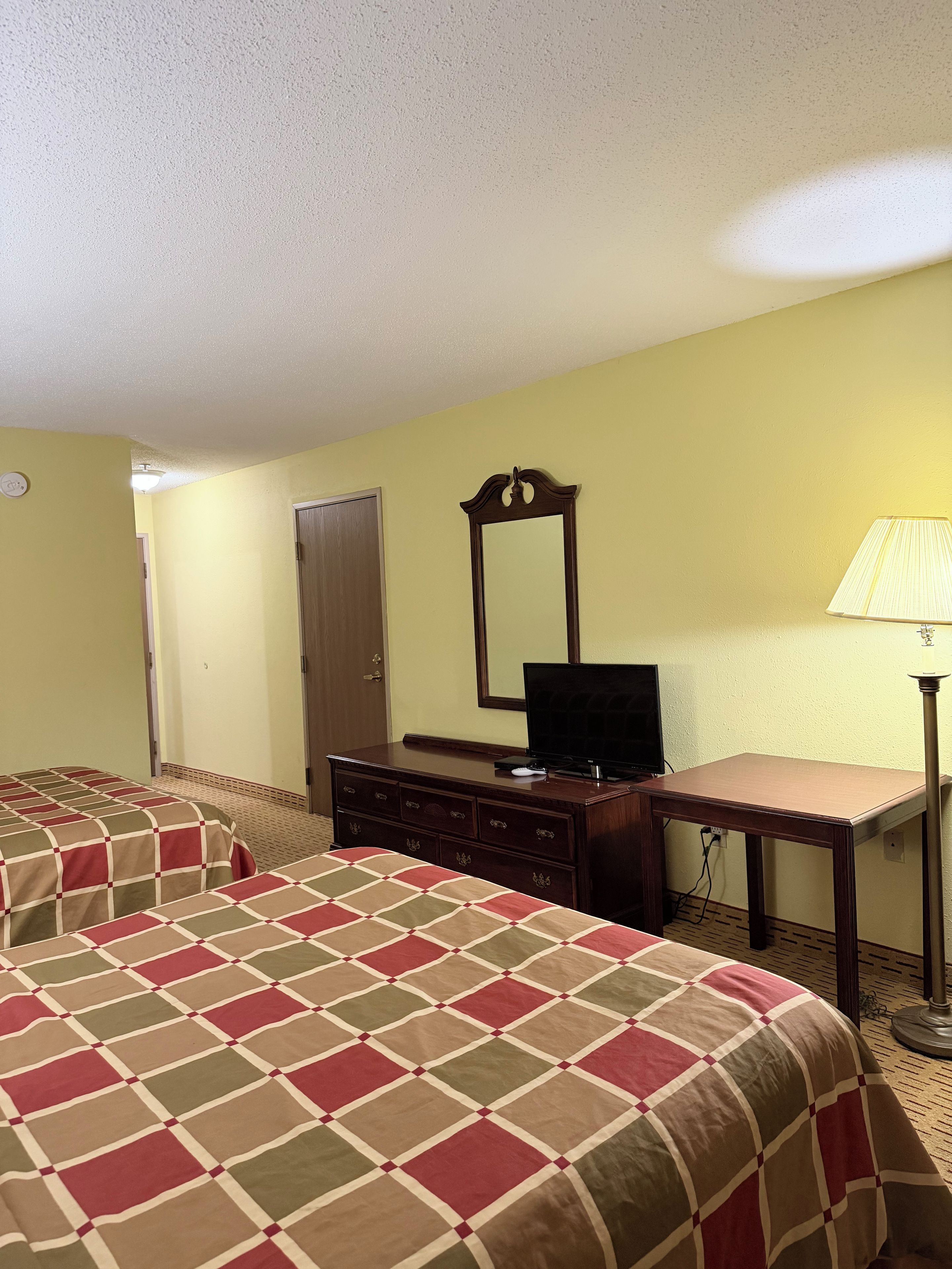 Habitación de hotel con dos camas, un aparador, un televisor y una lámpara.