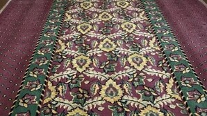Un long couloir étroit, doté d’un tapis à motifs, de murs blancs et d’une série de portes de chaque côté.