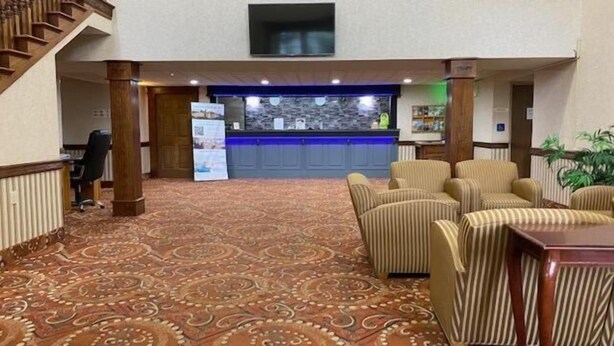 Un hall d’entrée avec un tapis à motifs, un comptoir de réception et un espace salon.