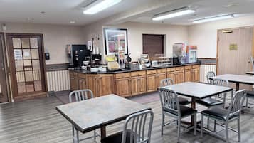 Ein Frühstücksbereich mit Kühlschrank, Toaster und Kaffeemaschine. Es gibt Tische und Stühle zum Essen.