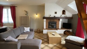 A living room with a sofa, a coffee table, a fireplace, and a television. - Petit Gite Lavie - Lucq-de-bearn (LUCQ-DE-BEARN)