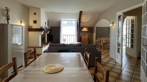 A spacious dining area with a large table and chairs, a kitchen with a built-in oven, and a cozy seating area with a sofa and a lamp. - Petit Gite Lavie - Lucq-de-bearn (LUCQ-DE-BEARN)