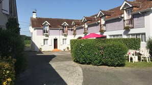 A row of white houses with brown tiled roofs, a hedge, and a red umbrella. - Petit Gite Lavie - Lucq-de-bearn (LUCQ-DE-BEARN)