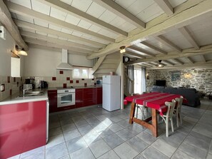 Una cocina con una isla central, una mesa de comedor con sillas, un muro de piedra y un sofá en la sala de estar.